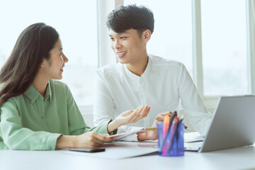 Obraz premium Young Asian business couple working together, completing the assigned work