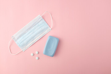 Surgical mask, medical pills and soap on pink background. Ideal concept of fighting Covid19