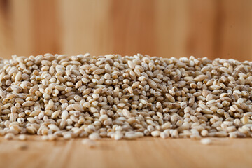 Close up of pearl barley grains scattered on wooden surface