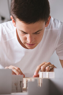 Close up of young architect working on a building project with a scale model.