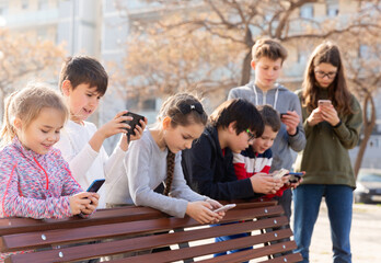 Group of children communicate using smartphones in the playground. High quality photo