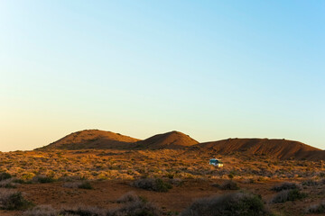 Van crossing a desert landscape at sunset