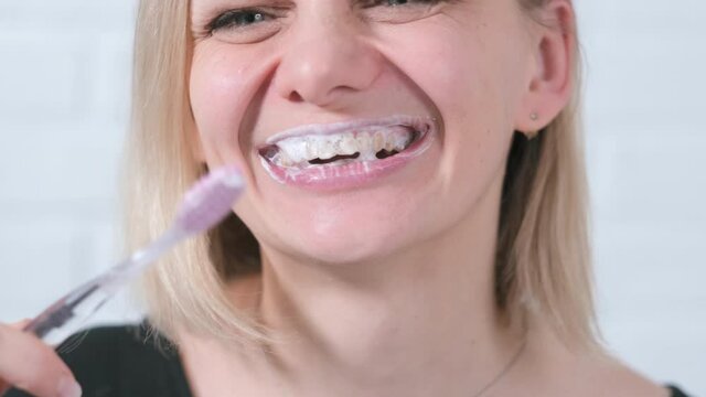 Smile close up young woman with toothbrush. middle age woman brushing teeth on white brick background. Health care, dental hygiene.