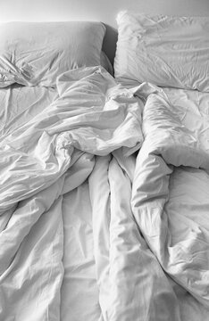 Grainy black and white of an unmade bed