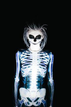Spooky portrait of woman in skeleton costume and halloween make up on black background
