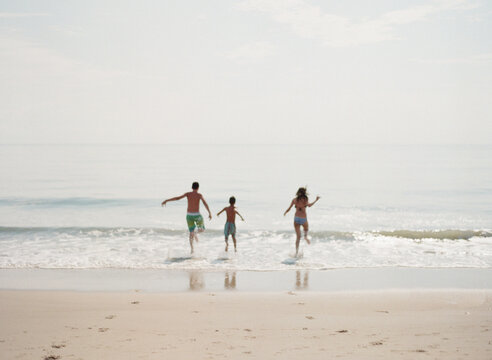 Three kids running into the ocean