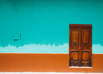 Wooden door with bright orange and aqua painted wall