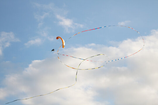 A paraglider flies with a long ribbon streamer