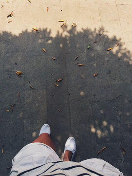 Pov of a woman wearing white in late summer walking down the street