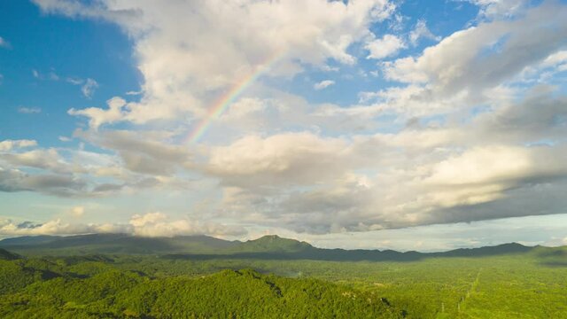 Hyper lapse 4K Amazing Rainbow after the rain over the forest. clouds time lapse. Mountain landscape, Rainbow in the mountains and dramatic clouds.