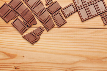 broken bar of chocolate on wooden background texture sweets