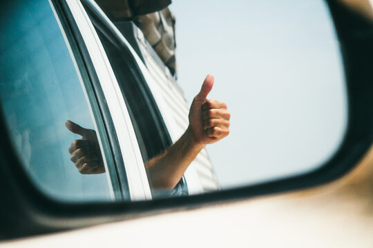 Thumbs up reflection on the mirror of a vehicle during an adventurous road trip