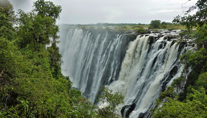 The powerful streams of Victoria Falls plunge into the abyss. The rocky channel of the Zambezi...