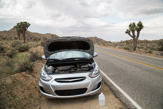 Car broken down on side of road in desert