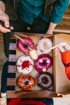 Birds eye view of two people eating a box of donuts