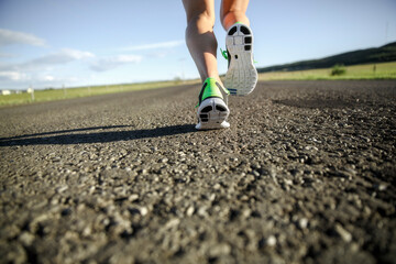 a close up of running shoes running away from camera down a paved road