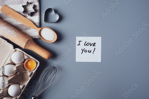Note I love you. Ingredients for making homemade cookies on a gray background. The concept of cooking sweets for Valentine's day, Father's Day or Mother's Day. Flat lay, top view