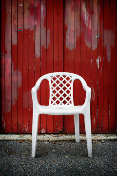 A three legged white plastic chair