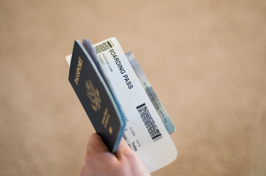 Closeup of a hand holding a passport with a boarding pass in it