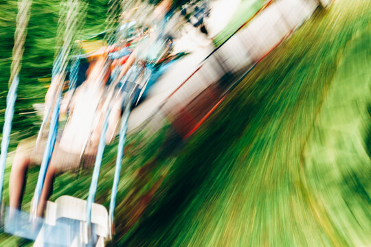 Unrecognizable people riding on a swing carousel in amusement park