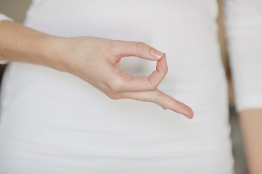 Woman in white dress making circle with fingers