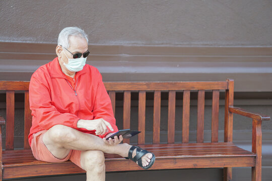 asian old elder senior man wearing face mask elderly using mobile smart phone cellphone. mature retirement lifestyle