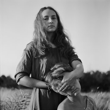 A black and white film portrait of young beautiful woman closing face of her friend