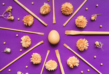 Easter Egg with brushes and flowers adn herbs on violet background.