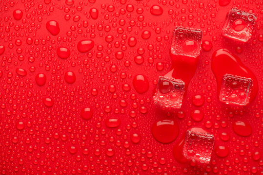 Top above overhead close up macro view photo of melting ice cubes on bright vivid color red background with drops