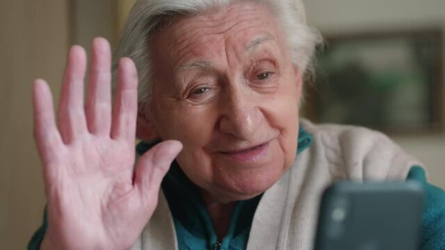 Cinematic shot of happy modern grandmother is using smartphone for navigate in internet, send messages and make calls at home. Concept of  technology, modern generation,family entertainment,connection