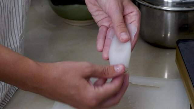 Female hand clean and cook fresh octopus or raw squids on home kitchen board