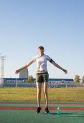 Teenager girl working out at the stadium doing jumping jacks