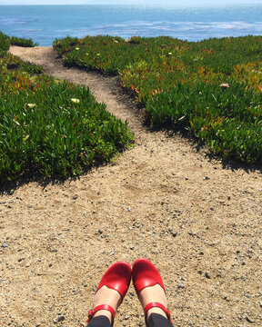 Female in red shoes sitting with an ocean view
