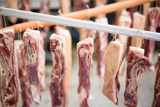 Several pieces of fat pork hanging on rope outdoor in daylight