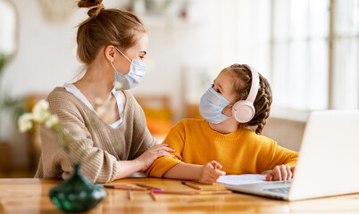 Mother helping daughter with remote education and  looking at each other during online lesson during pandemic