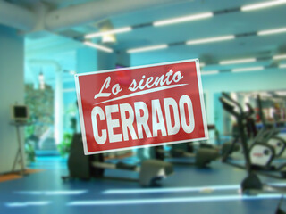 in Spanish inscription sorry we are closed. introducing forbidden measures for attending group classes. interior of empty modern gym