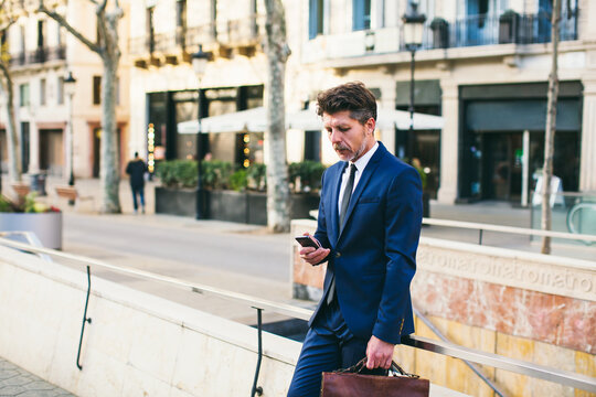 Mature businessman using his phone on the street.