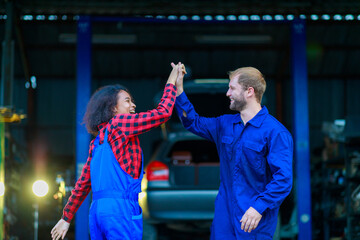 A happt couple mechanic stand in front of auto garage
