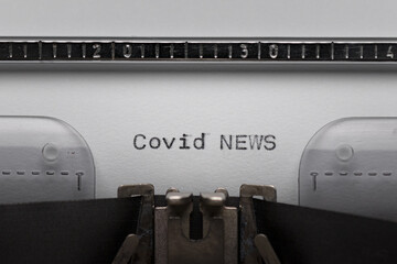 Typing text COVID NEWS on vintage manual typewriter. Close up of writes word on white paper. Shot...