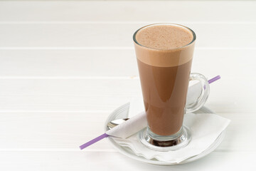 Glass cup of cocoa drink on white wooden table