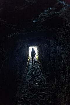 Brave woman walking through a dark tunnel in the mountains.