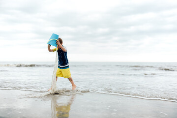 boy dumping water out of bucket