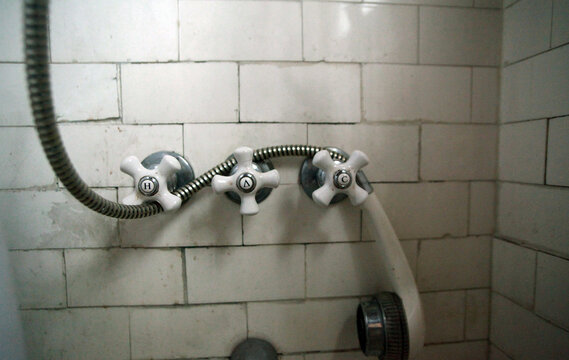 Vintage shower knobs and cord with with dirty tiles