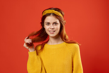 pretty emotional woman holding her hair Yellow sweater fashion red background