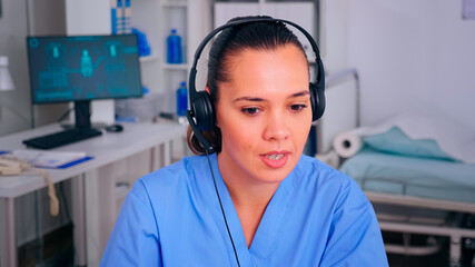 Specialist nurse answering using headphones checking appointment during telehealth communication in hospital. Healthcare physician in medicine clinic, receptionist doctor assistant helping with