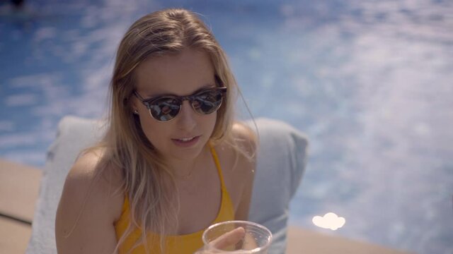 Close Up of a Caucasian Young Woman Sitting By the Pool and Sipping on a Drink