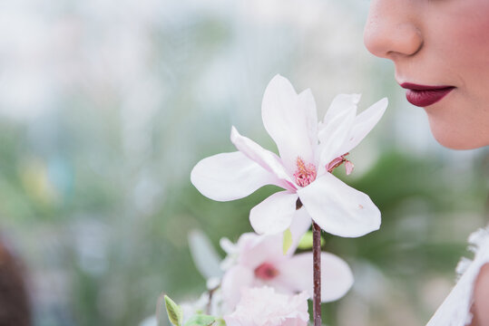 Young woman smelling a magnolia flower