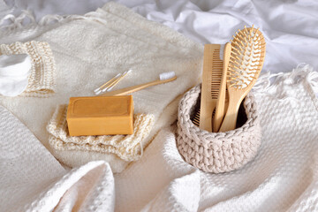 Fototapeta na wymiar Eco friendly morning care concept. wooden toothbrushes, combs, natural soap and other zero waste products on the bed with white linens