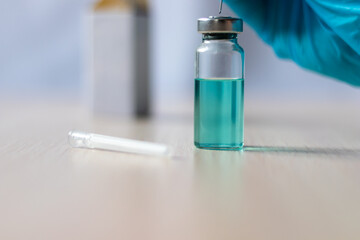 The gloved hand of a doctor or nurse holds a coronavirus vaccine.The concept of vaccination, medicine, and health care. Macro photography of a medical bottle with a vaccine. Selective focus.