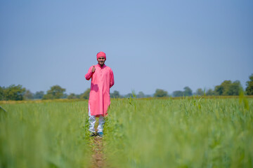 Naklejka na ściany i meble Young indian farmer standing his wheat field and giving happy expression